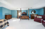 Spacious master bedroom with plush carpeting, featuring a four-poster bed and ample built-in storage.