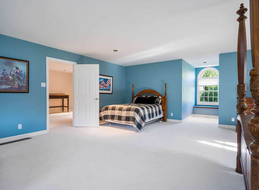 Spacious bedroom with light blue walls and plush carpeting.