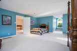 Spacious bedroom with light blue walls and plush carpeting.
