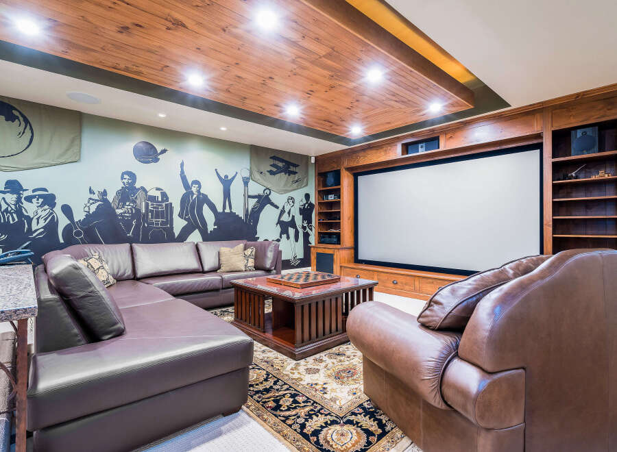 This luxurious home theater boasts a stunning wood-paneled ceiling and a large projection screen, perfect for movie nights.