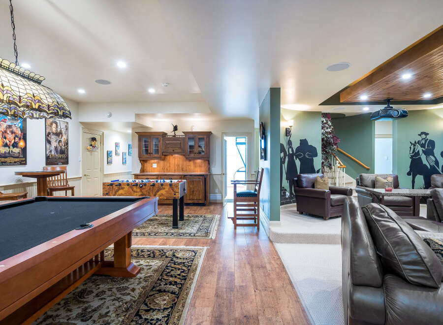 This stunning basement boasts a game room with a pool table, foosball table, and a home theater.
