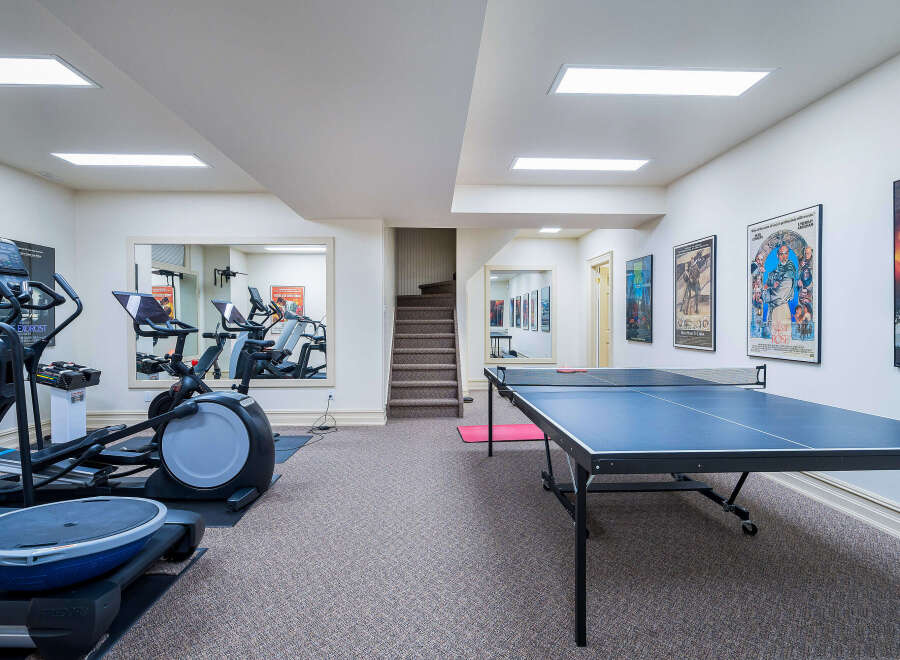 This stunning home boasts a fantastic recreation area featuring a fully equipped gym and a ping pong table, perfect for staying active and having fun.