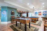 This stunning game room boasts a classic billiards table, foosball table, and a home theater, perfect for entertaining guests.