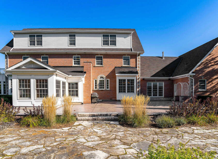 This stunning brick home boasts a spacious patio perfect for outdoor entertaining, complete with a flagstone walkway and lush landscaping.