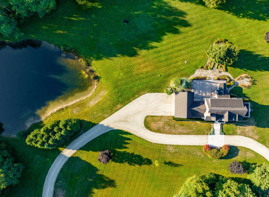 This stunning property boasts a spacious house with a large, inviting driveway, perfectly situated on a lush green lawn.