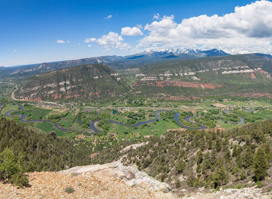 This stunning property boasts breathtaking panoramic views of a picturesque valley, complete with a meandering river and snow-capped mountains in the distance.