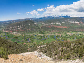 This stunning property boasts breathtaking panoramic views of a picturesque valley, complete with a meandering river and snow-capped mountains in the distance.