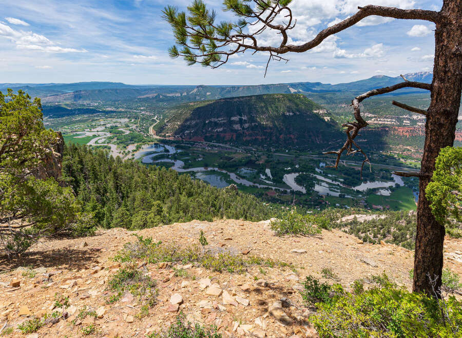 Spectacular panoramic view of a lush valley from a rocky mountain peak.