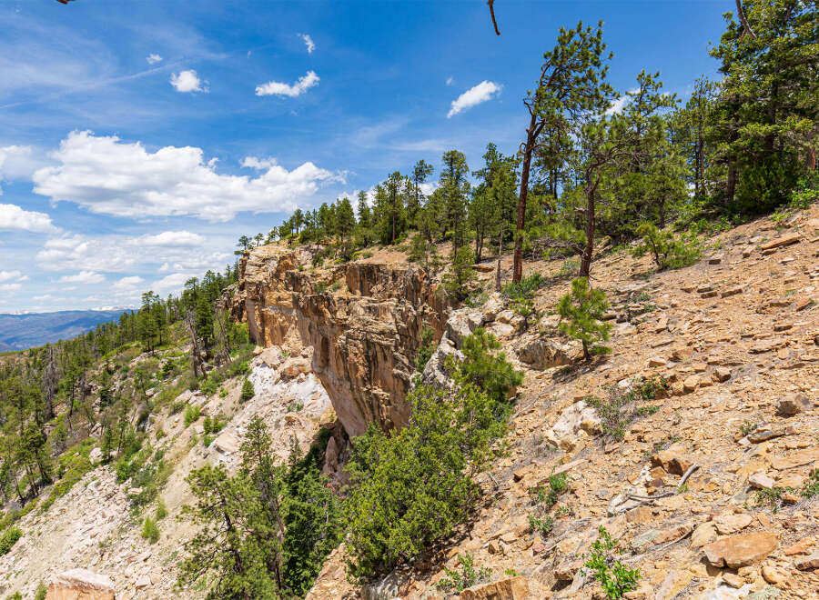 Spectacular vista of a cliffside landscape, showcasing a dramatic rock formation and lush greenery under a vibrant blue sky.