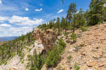 Spectacular vista of a cliffside landscape, showcasing a dramatic rock formation and lush greenery under a vibrant blue sky.