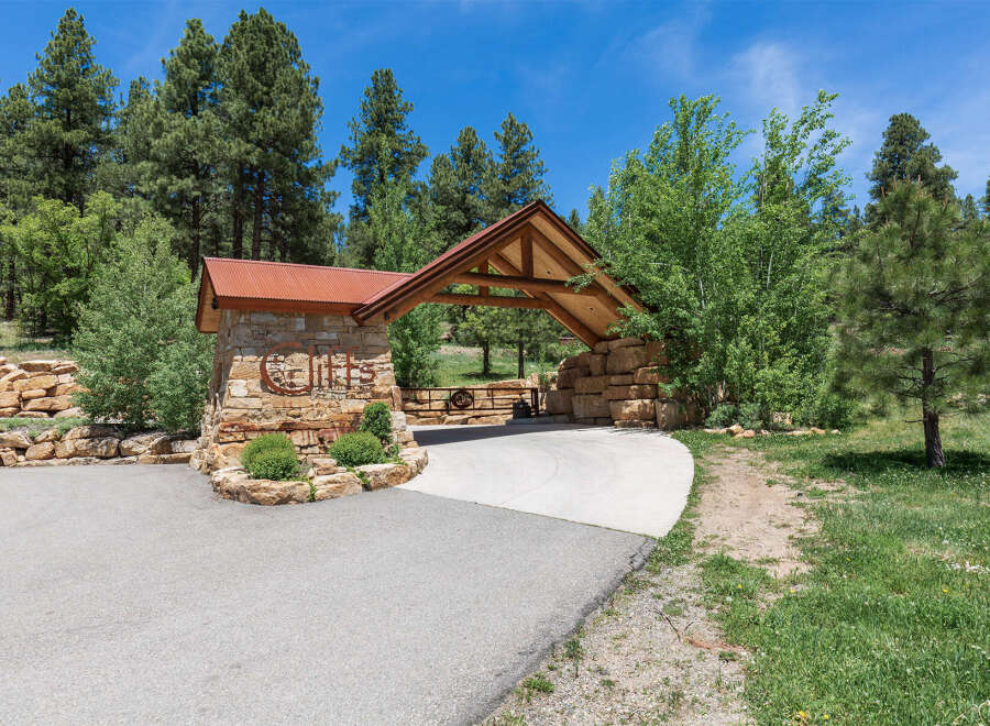 This stunning property boasts a picturesque entrance with a rustic wooden and stone archway, welcoming residents and guests alike.