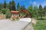 This stunning property boasts a picturesque entrance with a rustic wooden and stone archway, welcoming residents and guests alike.