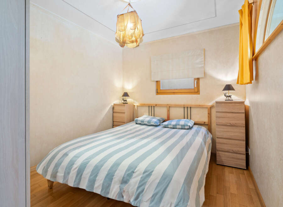 Cozy bedroom with striped bedding, wooden furniture, and a unique light fixture.