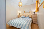 Cozy bedroom with striped bedding, wooden furniture, and a unique light fixture.