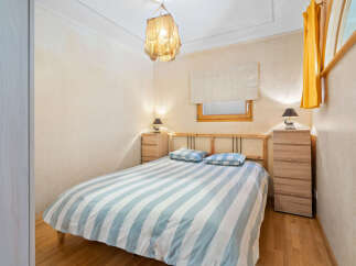 Cozy bedroom with striped bedding, wooden furniture, and a unique light fixture.