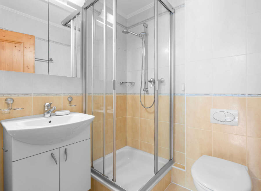 This charming bathroom boasts a modern glass shower enclosure, complemented by a sleek white sink vanity and toilet.