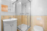This charming bathroom boasts a modern glass shower enclosure, complemented by a sleek white sink vanity and toilet.
