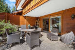 This stunning property boasts a spacious patio perfect for outdoor dining and relaxation, complete with comfortable wicker furniture and a wooden table.