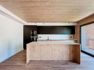 Modern kitchen with wooden island and dark cabinets.