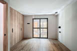 Bright and airy bedroom with built-in wooden wardrobe and large window offering ample natural light.