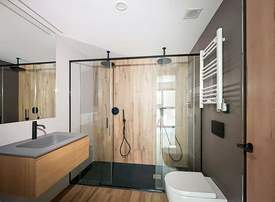 Modern bathroom with walk-in shower, sleek fixtures, and wooden vanity.