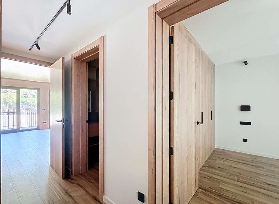 This stunning property boasts a bright and airy hallway with sleek wooden doors and modern light fixtures.