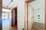 This stunning property boasts a bright and airy hallway with sleek wooden doors and modern light fixtures.