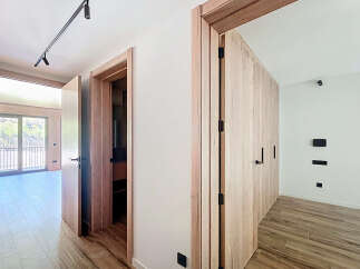 This stunning property boasts a bright and airy hallway with sleek wooden doors and modern light fixtures.