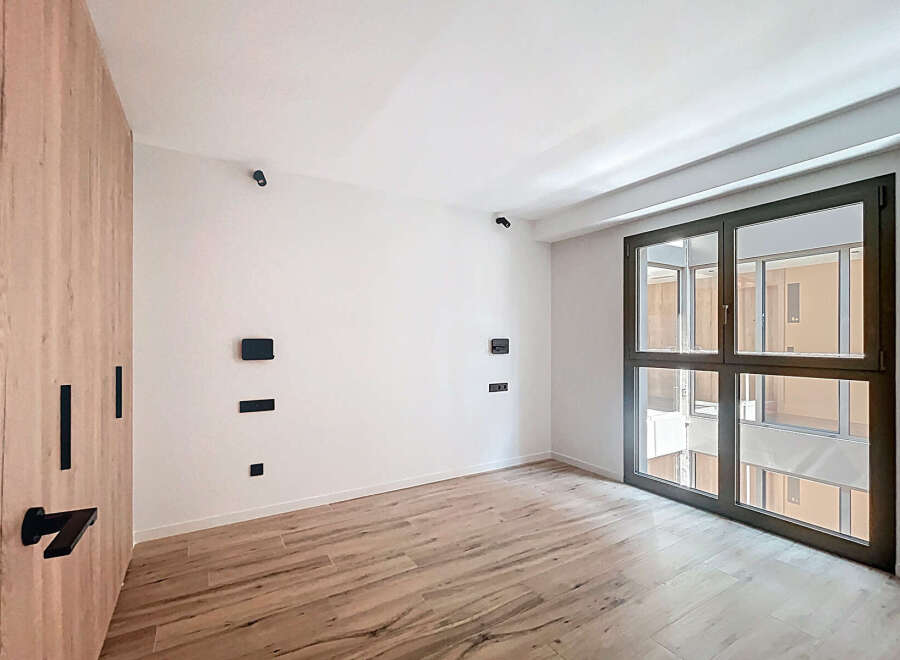 This stunning property boasts a spacious bedroom with sleek wooden flooring and large windows offering ample natural light.