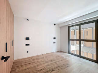 This stunning property boasts a spacious bedroom with sleek wooden flooring and large windows offering ample natural light.