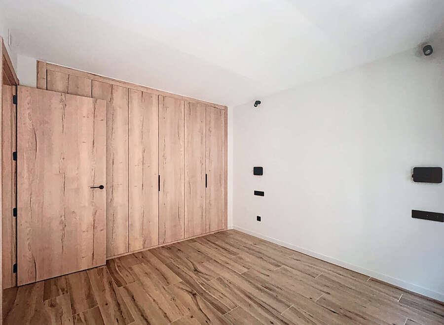 This stunning bedroom boasts a built-in wardrobe with light wood doors, offering ample storage space.