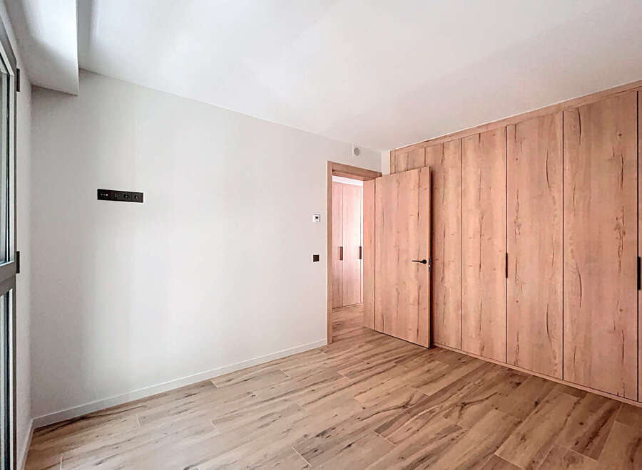 This stunning property boasts a spacious bedroom with sleek wooden flooring and built-in wardrobes.