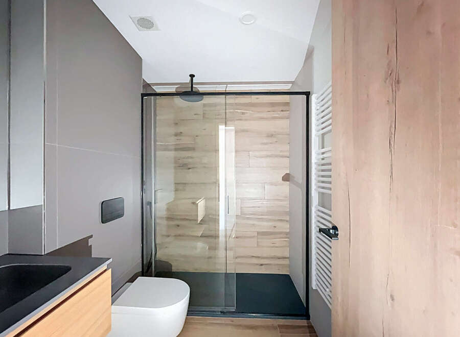 Modern bathroom with a sleek glass shower enclosure and wooden accents.