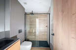Modern bathroom with a sleek glass shower enclosure and wooden accents.