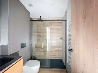 Modern bathroom with a sleek glass shower enclosure and wooden accents.