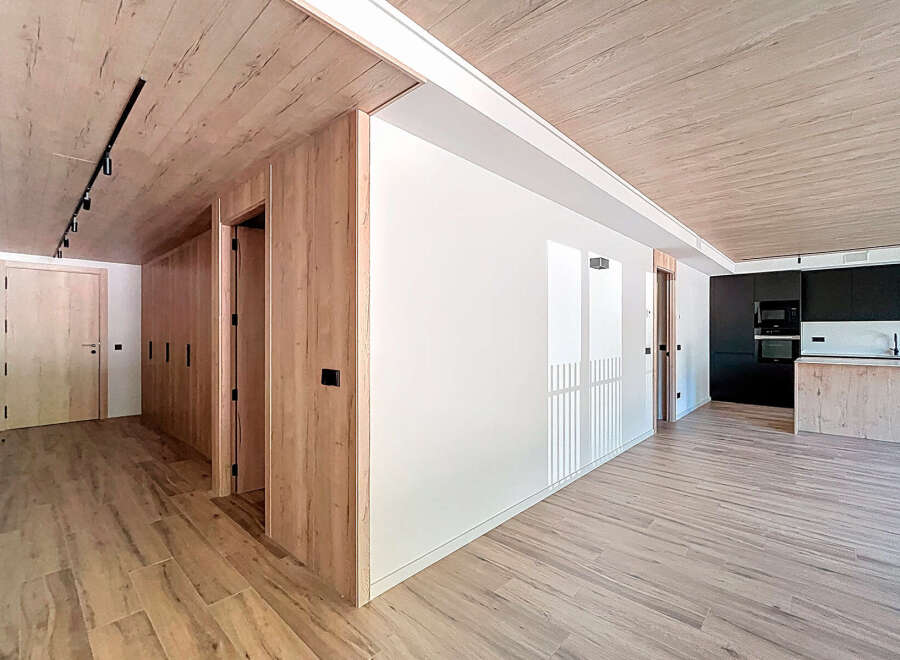 Stunning apartment boasts a spacious open-plan living area with sleek wooden flooring and a modern kitchen.