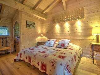Step into this cozy bedroom, featuring charming wooden walls and floors that exude warmth and rustic elegance.