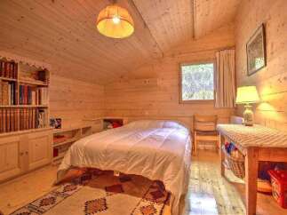 Discover the charm of this cozy bedroom, featuring warm wooden walls and a comfortable bed.