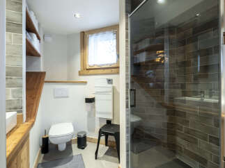 Modern bathroom with a walk-in shower, wooden shelving, and stylish gray tile flooring.