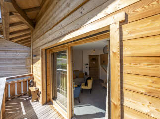 This stunning chalet boasts a spacious balcony with wooden decking, perfect for enjoying the mountain views.