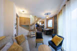Cozy living room with a modern and rustic design, featuring a comfortable sofa, armchairs, and a wooden staircase.