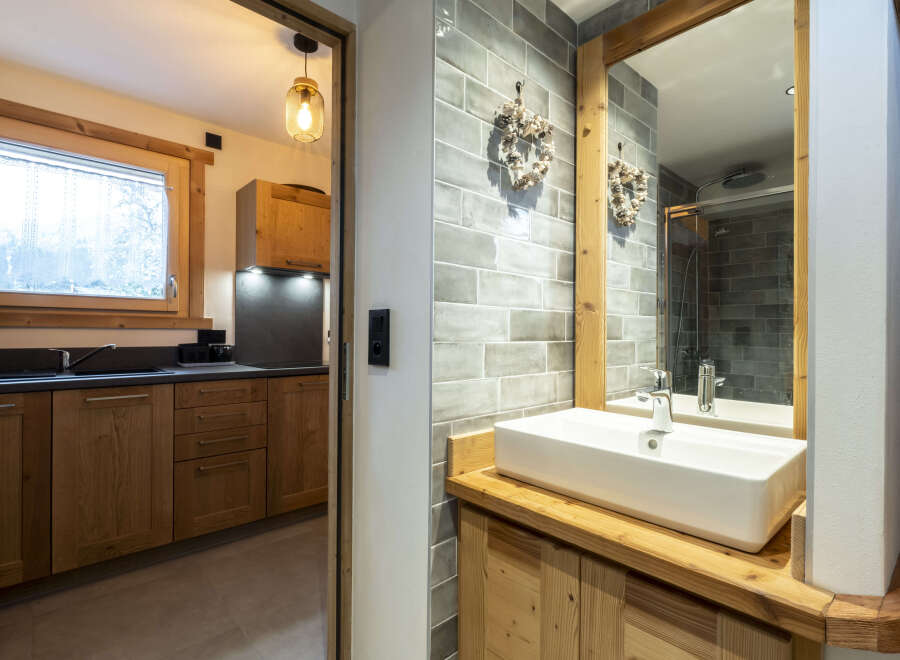 This stunning bathroom boasts a modern sink and wooden cabinetry, complemented by sleek grey tiles.