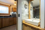 This stunning bathroom boasts a modern sink and wooden cabinetry, complemented by sleek grey tiles.