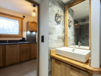 This stunning bathroom boasts a modern sink and wooden cabinetry, complemented by sleek grey tiles.