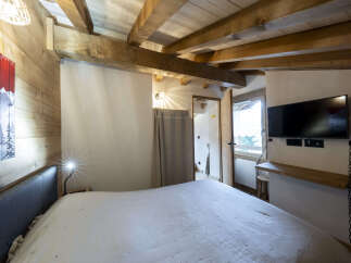 Cozy chalet bedroom with exposed wooden beams and a comfortable bed.