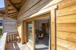 This stunning chalet boasts a spacious balcony with wooden decking, perfect for enjoying the mountain views.