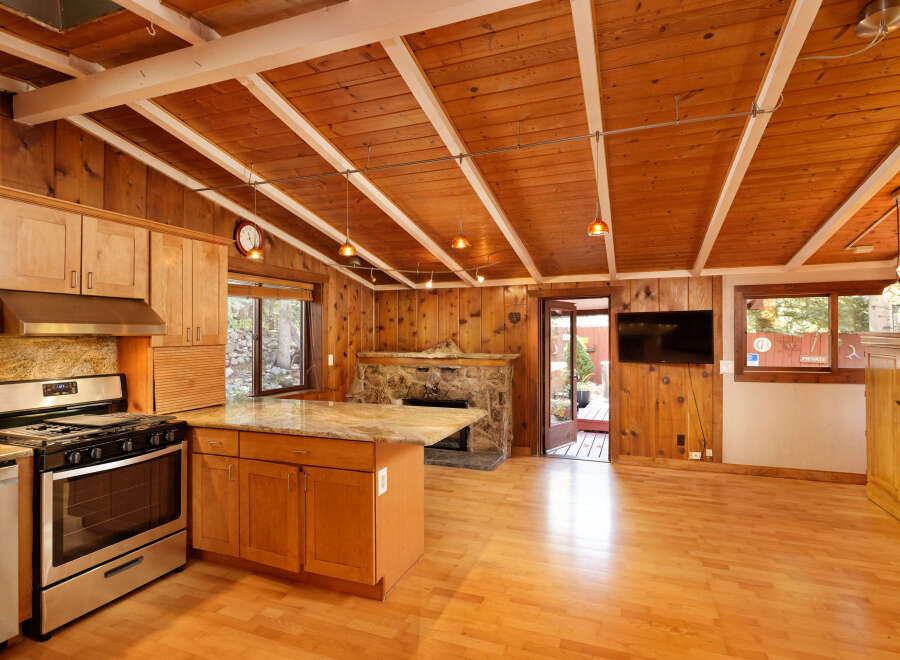 This charming cabin boasts a spacious kitchen with granite countertops and wooden cabinetry, complemented by a cozy stone fireplace.