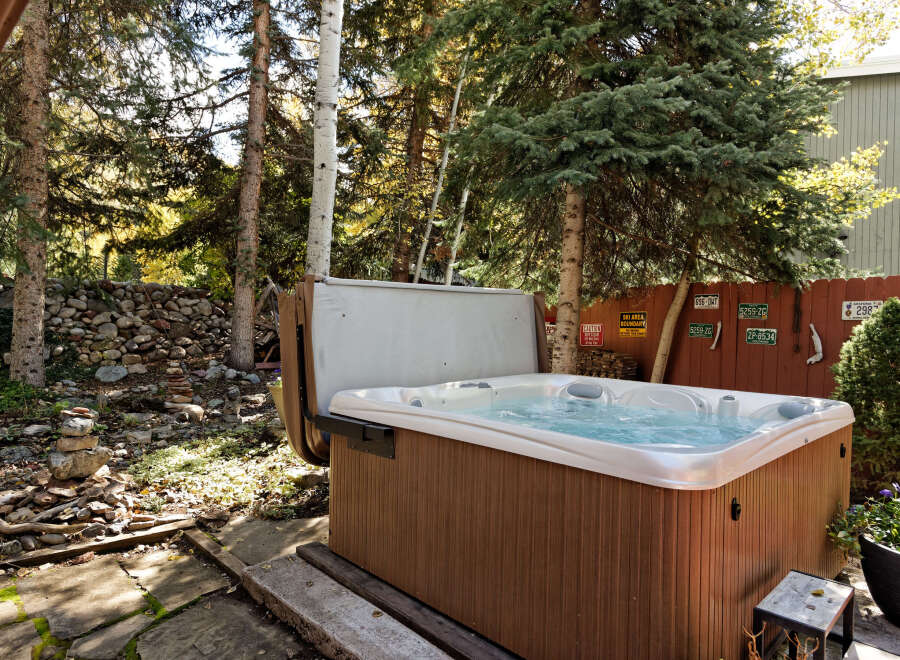 Relax and rejuvenate in your private hot tub, nestled amidst a serene wooded backdrop.