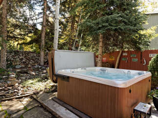 Relax and rejuvenate in your private hot tub, nestled amidst a serene wooded backdrop.