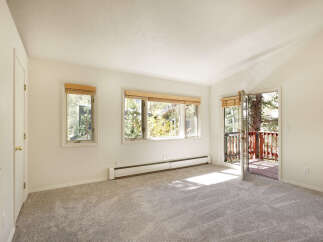 Bright and spacious bedroom with plush carpeting, large windows offering abundant natural light, and a private balcony access.